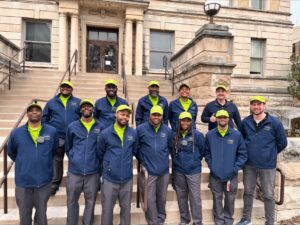 A group of individuals wearing matching uniforms outside of a governmental building.