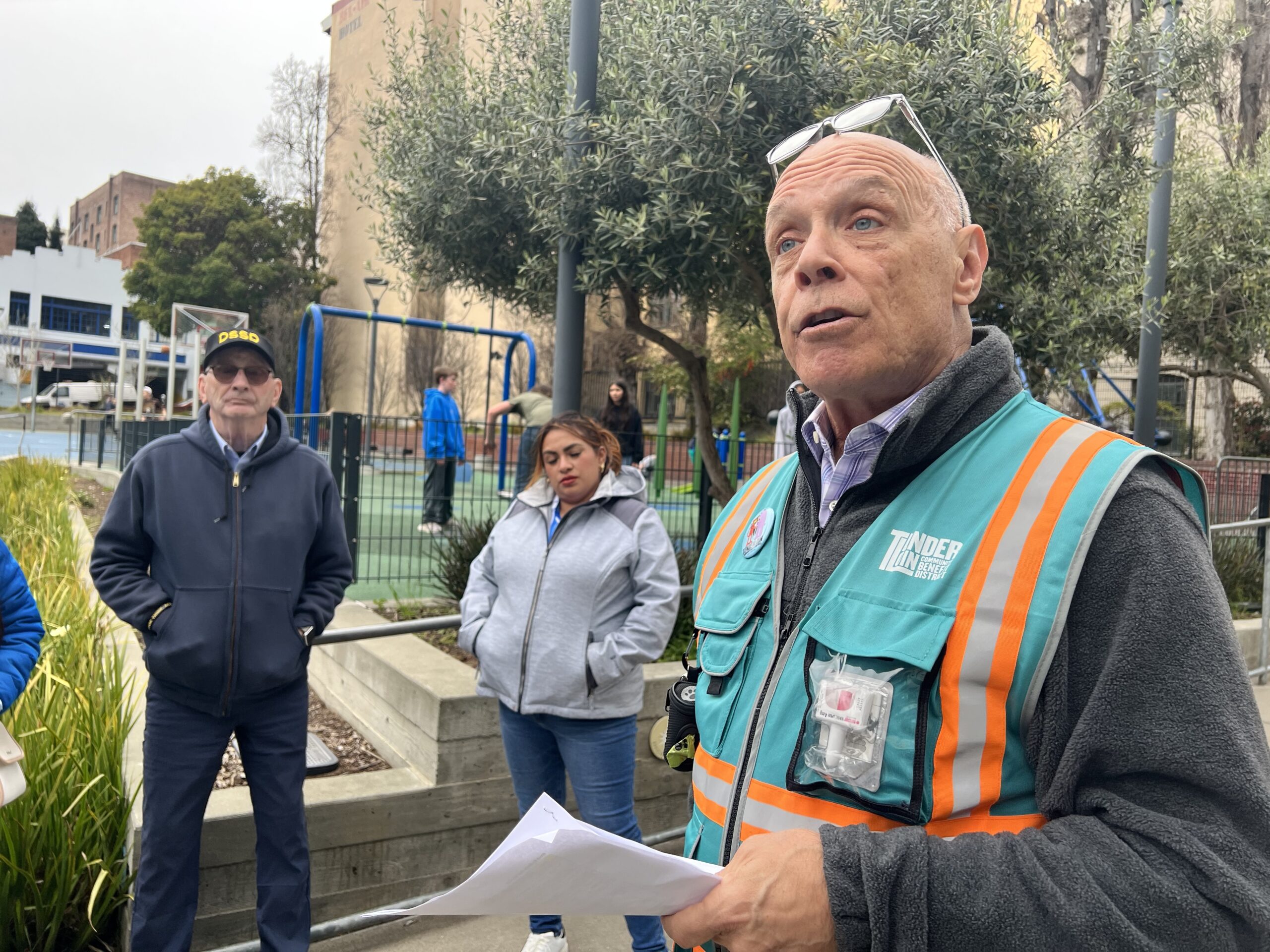 A man in a safety vest speaks to a group.